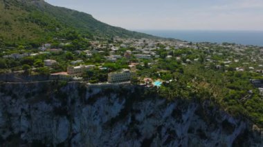 Yüksek kayalıkların üstündeki lüks konutların kayma ve yan çekimleri. Seyahat noktasında tropik deniz manzarası. Capri, Campania, İtalya.