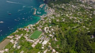 Yaz tatilinde deniz kıyısının yüksek açılı manzarası. Eğim su yüzeyinde yüksek kayalıkları olan çıkıntıları ortaya çıkarır. Capri, Campania, İtalya.