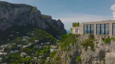 İleri uçaklar Akdeniz 'de, şehrin yukarısındaki yüksek kayalıklarda modern konutun etrafında uçuyor. Capri, Campania, İtalya.