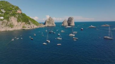 Kayalık kıyıya demir atmış yatların ve yelkenlilerin hava kaydırak ve pan görüntüleri. Akdeniz 'de güneşli bir gün. Capri, Campania, İtalya.