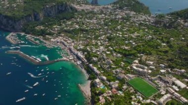 Deniz kıyısındaki binaların yüksek açılı manzarası. Limanda ve kıyı boyunca turkuaz suda böbürlen. Capri, Campania, İtalya.