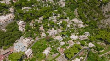Yokuştaki evler ve ağaçların yüksek açılı manzarası. Denizi ve Vesuvius Yanardağı 'nı uzaktan göster. Capri, Campania, İtalya.