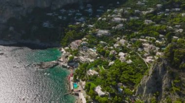 Deniz kıyısından yükselen yamaçtaki konukevleri ve konukevleri yüksek açılı görüyor. Güneşli bir günde yolculuk rotası. Capri, Campania, İtalya.