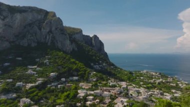 Yüksek kaya duvarının altındaki sahil kasabasının muhteşem manzarası. Taş yığınının tepesindeki ünlü Villa Castiglione 'nin tersten görüntüsü. Capri, Campania, İtalya.