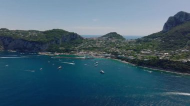 Deniz kıyısındaki teknelerin ve kayalık yamaçlar arasındaki kasabanın havadan panoramik görüntüsü. Capri, Campania, İtalya.
