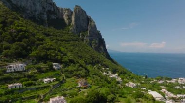 İleriye doğru güzel deniz manzarasının üzerinde uçar. Ünlü seyahat merkezlerinde lüks evler ve arka planda yüksek kayalar. Capri, Campania, İtalya.