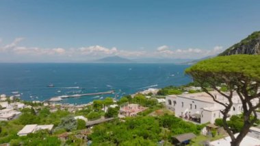 Deniz kıyısının havadan panoramik görüntüsü ve uzaktaki görkemli Vezüv Dağı. Kasabadaki evlerin tersten görünümü. Capri, Campania, İtalya.