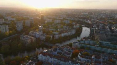 Nehir boyunca yerleşim yerinin üzerinden uç. Gün batımında şehrin havadan panoramik görüntüsü. Berlin, Almanya.