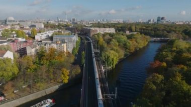 Köprüden geçen yolcu treninin hava görüntüsü. Ünlü Fernsehturm ile büyük Tiergarten parkı ve şehir manzarasının yükselişi. Berlin, Almanya.