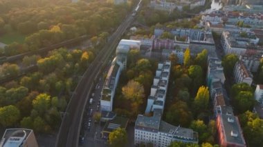 Şehir merkezindeki ve nehri geçen demiryollarının yüksek açılı görüntüsü. Ulaşım altyapısının havadan görünüşü altın saatinde sonbahar ağaçlarıyla çevrilidir. Berlin, Almanya.