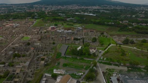 歴史的な観光名所の上を飛ぶ ポンペイの古代都市の遺跡と背景にヴェスヴィオ山火山を明らかに傾きます ポンペイ イタリア — ストック動画