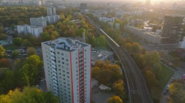 Modern yüksek katlı apartmanın havadan kayma ve pan görüntüleri. S Bahn treni raylardan geçiyor. Öğleden sonra ağaçlarda sonbahar yaprakları. Berlin, Almanya.