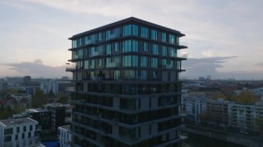 Nehir kıyısındaki modern yüksek apartmanın yörüngesinde. Günbatımında yerleşim bölgesi. Berlin, Almanya.