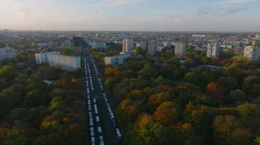 Sonbahar parkında geniş yolda park etmiş otobüslerin üzerinde ilerliyorlar. Tiergarten ve çevresindeki yerleşim yerleri gün batımında. Berlin, Almanya.