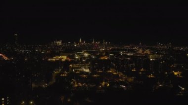 Gece metropolün üzerinde ilerliyorlar. Aydınlatılmış binaların ve caddelerin hava manzarası. New York City, ABD.