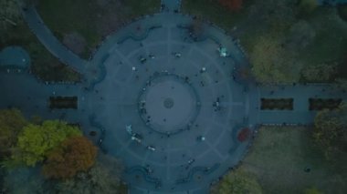 Sonbahar ağaçlarıyla çevrili, parktaki dairesel taşlı maça kaydının en tepeye yükselen görüntüsü. İnsanlar parkta dinleniyor. New York City, ABD.