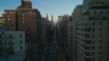 Metropolis 'teki caddenin ve etrafındaki binaların havadan yükselen görüntüleri. Günbatımında modern gökdelenlerle şehir manzarasını gözler önüne sermek. New York City, ABD.