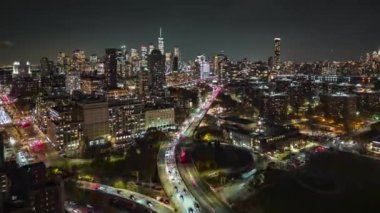 Gece metropolünün hava panoramik hızlandırılmış görüntüsü. Akşam trafiği yoğun ve arka planda Manhattan gökdelenleri var. New York City, ABD.