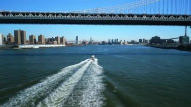 Nehir boyunca uzanan köprünün altından geçen sürat teknesi. Güneşli bir günde şehirde gemi takibi. New York City, ABD.