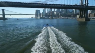 Köprünün altından geçen küçük bir geminin izini sürüyorum. Manhattan 'ın ikonik gökdelenleriyle gökdelenler açılıyor. New York City, ABD.