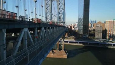 Manhattan Köprüsü 'nün alt güvertesinde East River üzerinde giden metro treninin izini sürüyorum. İleriye doğru gölgeler boyunca uçun. New York City, ABD.