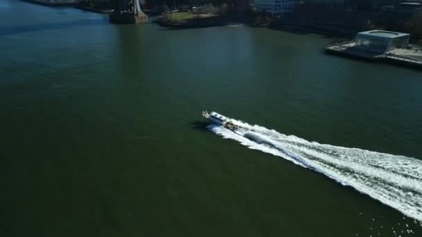 水上を走行し 波を作るモーターボートの高角度ビュー 大都市の鉄橋や建物の明らかに傾きます 米国ニューヨーク市 — ストック動画