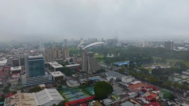 Aerial descending footage of buildings in city. Mixture of multistorey and low residential buildings and sport venues. San Jose, Costa Rica.