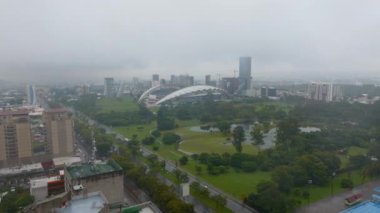 Aerial view of large green park with trees in city. La Sabana Park and Estadio Nacional de Costa Rica on rainy day. San Jose, Costa Rica.