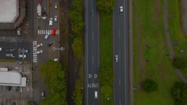 Birds eye shot of transport infrastructure in town. Cars passing road intersection and road leading along with rail track. San Jose, Costa Rica.