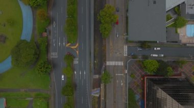 Top down with of low traffic on roads in city. Vehicles driving on multilane road along green park. San Jose, Costa Rica.