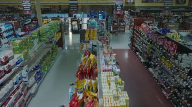 Fly above shelves in empty shop. Revealing checkout zone. Interior of large supermarket outside opening hours.