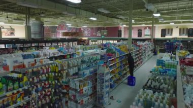 Worker replenishing and arranging products on shelves after store is closed. Interior of large supermarket outside opening hours.