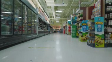 Boş bir dükkanda raflar ve eşyalar arasında alçaktan uçmak. Dondurulmuş mallar bölümü. Açılış saatleri dışındaki büyük süpermarketin içi.