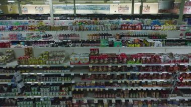 Forwards fly above aisles and shelves with products in shop. Interior of large supermarket outside opening hours.