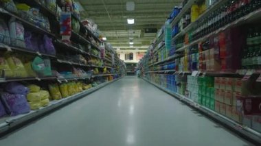 Empty shop after closing. Low flight on aisle between shelves. Interior of large supermarket outside opening hours.