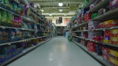 Backwards revealing of goods arranged on shelves. Fly in empty shop. Interior of large supermarket outside opening hours.