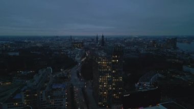 Modern design Tanzende Turme and other buildings along famous Reeperbahn street at dusk. Backwards fly above evening city. Hamburg, Germany.