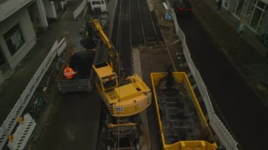 Şehirdeki tramvay raylarının arasına asfalt koyan makinelerin hava görüntüleri. Toplu taşıma altyapısının yenilenmesi. Berlin, Almanya.