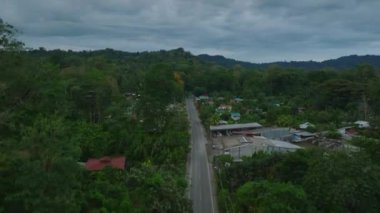 Aerial view of village with low poor houses surrounded by dense green vegetation. Revealing vast tropical forest. Puerto Viejo, Costa Rica.