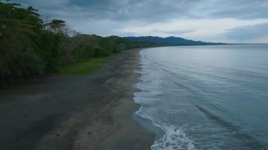 Kum kıyılarını yıkayan deniz suyunun havadan görünüşü. İleriye doğru tropikal istikamette kıyı şeridi üzerinde uçar. Puerto Viejo, Kosta Rika.