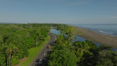 Top view of river flowing near a empty white sand beautiful tropical beach. Bridge causeway over a river flowing near pacific ocean coastline