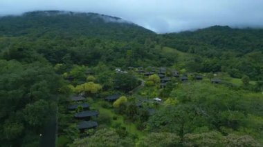 Forwards fly above accommodation resort in nature. Complex of small bungalow cabins surrounded by forest. La Fortuna, Costa Rica.