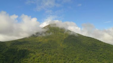 Aerial slide and pan footage of majestic cone shape of Arenal volcano with clouds around top. La Fortuna, Costa Rica.