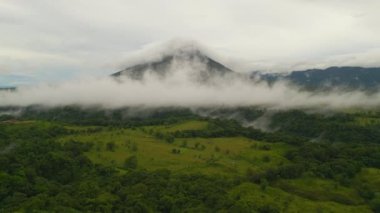 Tropikal manzaranın hava panoramik görüntüsü. Görkemli Arenal volkanı bulutlarla örtülü. La Fortuna, Kosta Rika.