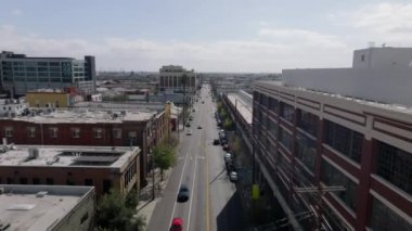 Şehirdeki uzun düz caddenin üzerinde ilerliyorlar. Şehir merkezinde şehir planlamasıyla çevrili bir yol. Los Angeles, Kaliforniya, ABD.