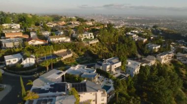 Hollywood Hills 'teki lüks konutların ve villaların üzerinden geriye doğru uçuyor. Şehir merkezindeki gökdelenler. Los Angeles, Kaliforniya, ABD.