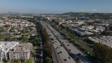 Düz arazideki büyük şehrin havadan panoramik görüntüsü. Metropolis 'teki çok şeritli otoyolda giden araba dereleri. Los Angeles, Kaliforniya, ABD.