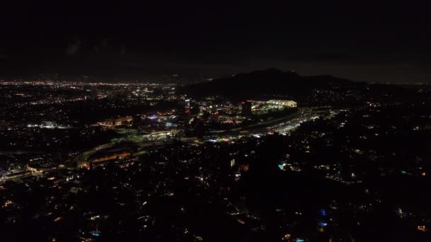 前方夜市の上を飛ぶ ユニバーサルシティの照明付き建物の周りのマルチレーン高速道路を走行車 米国カリフォルニア州ロサンゼルス — ストック動画