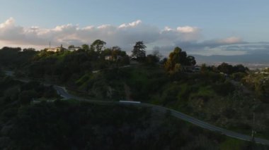 İleri, büyük şehrin tepelerindeki lüks evlerinin üzerinden uçar. Alacakaranlıktaki şehir merkezinin hava görüntüleri. Los Angeles, Kaliforniya, ABD.