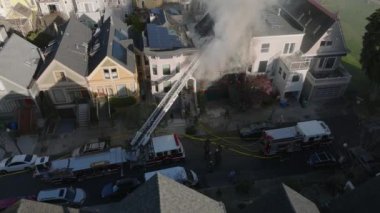 Şehir merkezindeki bir evde profesyonel itfaiyecilerin yangına müdahalesinin hava kaydırak ve pan görüntüsü. San Francisco, California, ABD